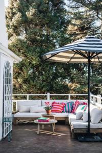 a patio with couches and an umbrella on a deck at Treehouse Southern Highlands in Moss Vale