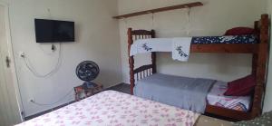 a bedroom with two bunk beds and a flat screen tv at Loft Praia do Sonho in Itanhaém