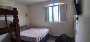 a bedroom with a bed and a window at Loft Praia do Sonho in Itanhaém +3 photos