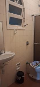 a bathroom with a sink and a toilet and a mirror at Loft Praia do Sonho in Itanhaém