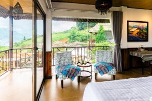 a room with a bed and two chairs and a balcony at Larosa Homestay Sapa in Sa Pả