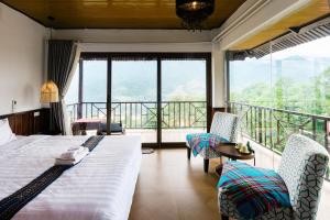 a bedroom with a bed and chairs and a balcony at Larosa Homestay Sapa in Sa Pả