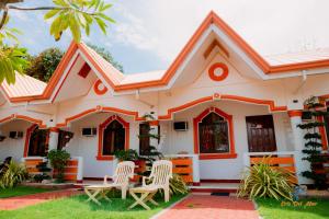 a house with two chairs in front of it at Cris Del Mar Resort in Bolinao +3 photos