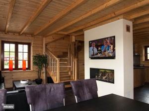 a living room with a fireplace and a tv on the wall at Houten villa Tine in Den Ham