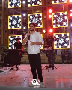 a man standing on a stage holding a microphone at Biu Bela abartment hotel in El Alamein
