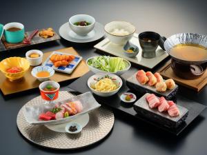a table with plates of sushi and bowls of food at Resorpia Beppu in Beppu
