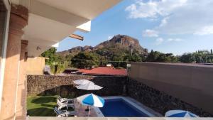 a balcony with an umbrella and chairs and a swimming pool at Nuevo Amanecer in Tepoztlán