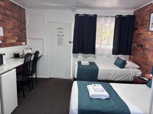 a small room with two beds and a kitchen at Avocado Motor Inn in Childers