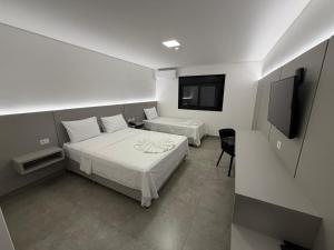 a bedroom with two beds and a flat screen tv at Hotel Morada do Sol in Chavantina +41 photos