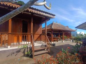 a wooden house with a porch and a balcony at Pondok DG and Spa in Munduk