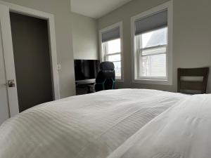 a bedroom with a white bed with a chair and a television at Airport room with free parking in Boston