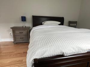 a bed with a white blanket and a nightstand with a lamp at Airport room with free parking in Boston