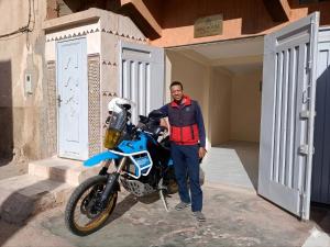 a man is standing next to a blue motorcycle at Aziz House 1 Tan Tan in Tan-Tan
