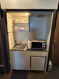 a small kitchen with a sink and a microwave at 竹葉庵 in Nagaokakyo