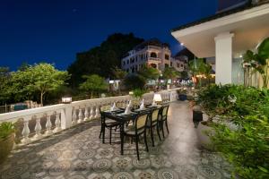 a table and chairs on a balcony at night at Maison Cat Ba Bay View Villa in Cat Ba