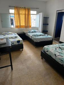 a room with three beds and a table and window at Guiapa en melgar in Melgar