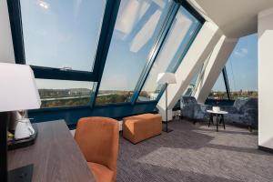a room with tall windows and chairs and a table at Excelsior Hotel Nürnberg Fürth, a member of Radisson Individuals in Fürth