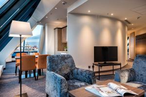 a living room with chairs and a tv and a table at Excelsior Hotel Nürnberg Fürth, a member of Radisson Individuals in Fürth