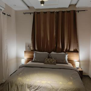 a bedroom with a large bed with a brown curtain at Le Cocon coloré Work and Chill KÉgué in Avéimé