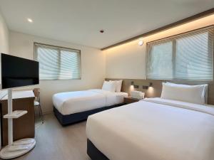 a hotel room with two beds and a flat screen tv at Link B Hotel in Busan