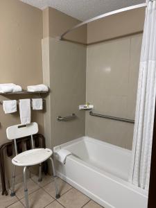 a bathroom with a bath tub and a stool at LaVale Inn Cumberland Area in La Vale