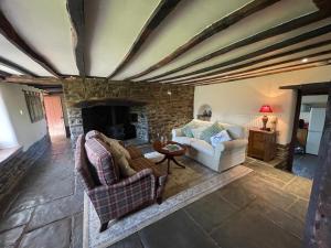 a living room with two couches and a stone fireplace at 16th Century Devon Farmhouse Stunning Views in Winkleigh