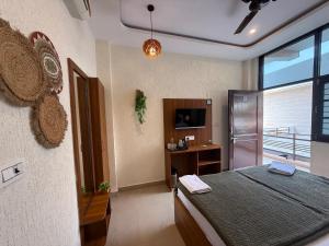 a bedroom with a bed and a desk and a television at Moon and Root in Narendranagar
