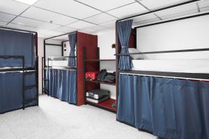 a room with two bunk beds with blue curtains at Kinboshi Silom in Bangkok
