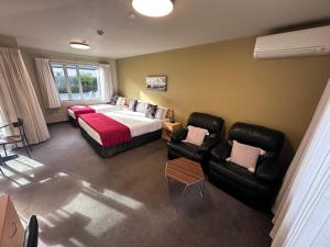 a bedroom with a bed and a couch and chairs at ASURE Centrepoint Motel in Christchurch +41 photos