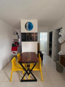 a dining room with a wooden table and yellow chairs at Aconchego estrada do coco in Camaçari