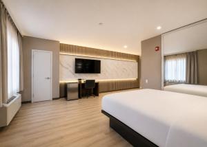 ein Hotelzimmer mit Bett, Schreibtisch und Fernseher in der Unterkunft Hotel Pergola Jamaica JFK in Queens