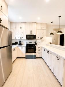 a kitchen with white cabinets and a stainless steel refrigerator at Gold'n Retreat in Mission