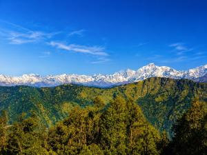 a mountain range with snow capped mountains in the background at Hotel vidya om palace in Ukhimath