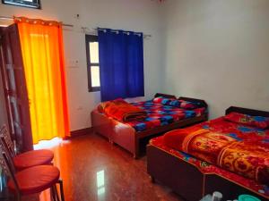 a room with two beds and a window with curtains at Hotel vidya om palace in Ukhimath