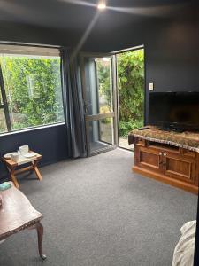 a living room with a flat screen tv and a couch at Private and comfortable guesthouse in Christchurch