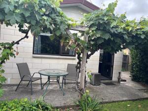a patio with a table and chairs and a tree at Private and comfortable guesthouse in Christchurch