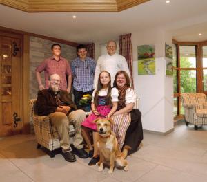 a family posing for a picture in a living room with a dog at Hotel Schwarzwald-Gasthof Rößle in Todtmoos