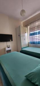 a bedroom with two green beds and a flat screen tv at Mali's Apartment in Tirana