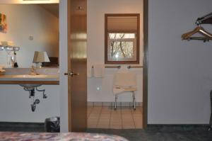 a bathroom with a sink and a mirror and a chair at Moriah Motel in Sheridan