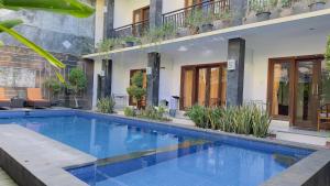 a swimming pool in front of a building at Waringin Homestay in Kuta