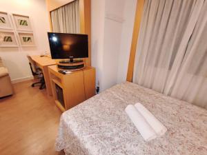 a bedroom with a bed with a television and a desk at Flat Aeroporto Congonhas in São Paulo