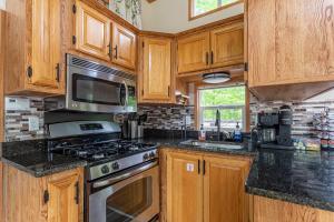 a kitchen with wooden cabinets and a stove top oven at The Nook Tiny Home Fire Pit Close to Lake in Maple Lake