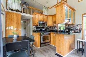 a kitchen with wooden cabinets and a black table at The Nook Tiny Home Fire Pit Close to Lake in Maple Lake