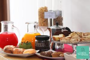 - une table avec deux assiettes de viennoiseries et de jus d'orange dans l'établissement B&B La Corte degli Spada - Borgo Antico del Salento, à Mesagne