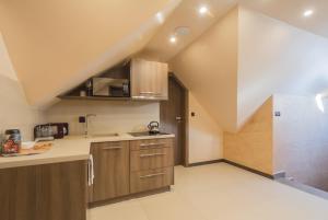 an attic kitchen with wooden cabinets and a sink at Poduszka Goprówka in Szczawnica