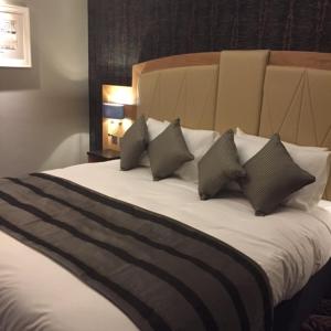 a bedroom with a bed with four pillows at The Bell Hotel Aylesbury in Aylesbury