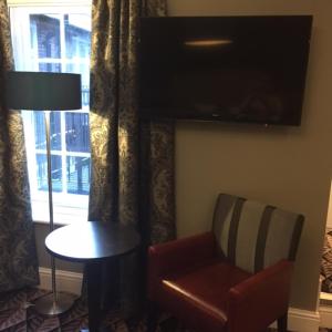 アリスバーリーにあるThe Bell Hotel Aylesburyの椅子、テーブル、テレビが備わる客室です。