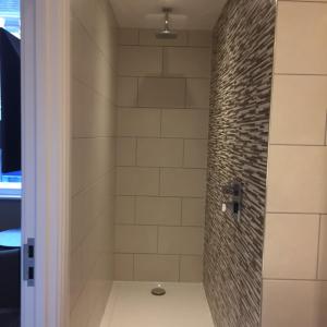 uma casa de banho com um chuveiro e uma parede de tijolos em The Bell Hotel Aylesbury em Aylesbury