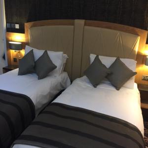 two beds in a hotel room with pillows on them at The Bell Hotel Aylesbury in Aylesbury