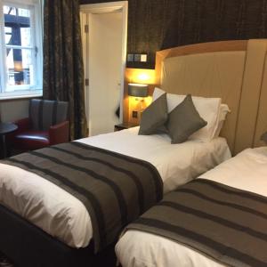 a hotel room with two beds and a chair at The Bell Hotel Aylesbury in Aylesbury